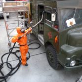 Man in orange suite removing asbestos from a vehicle