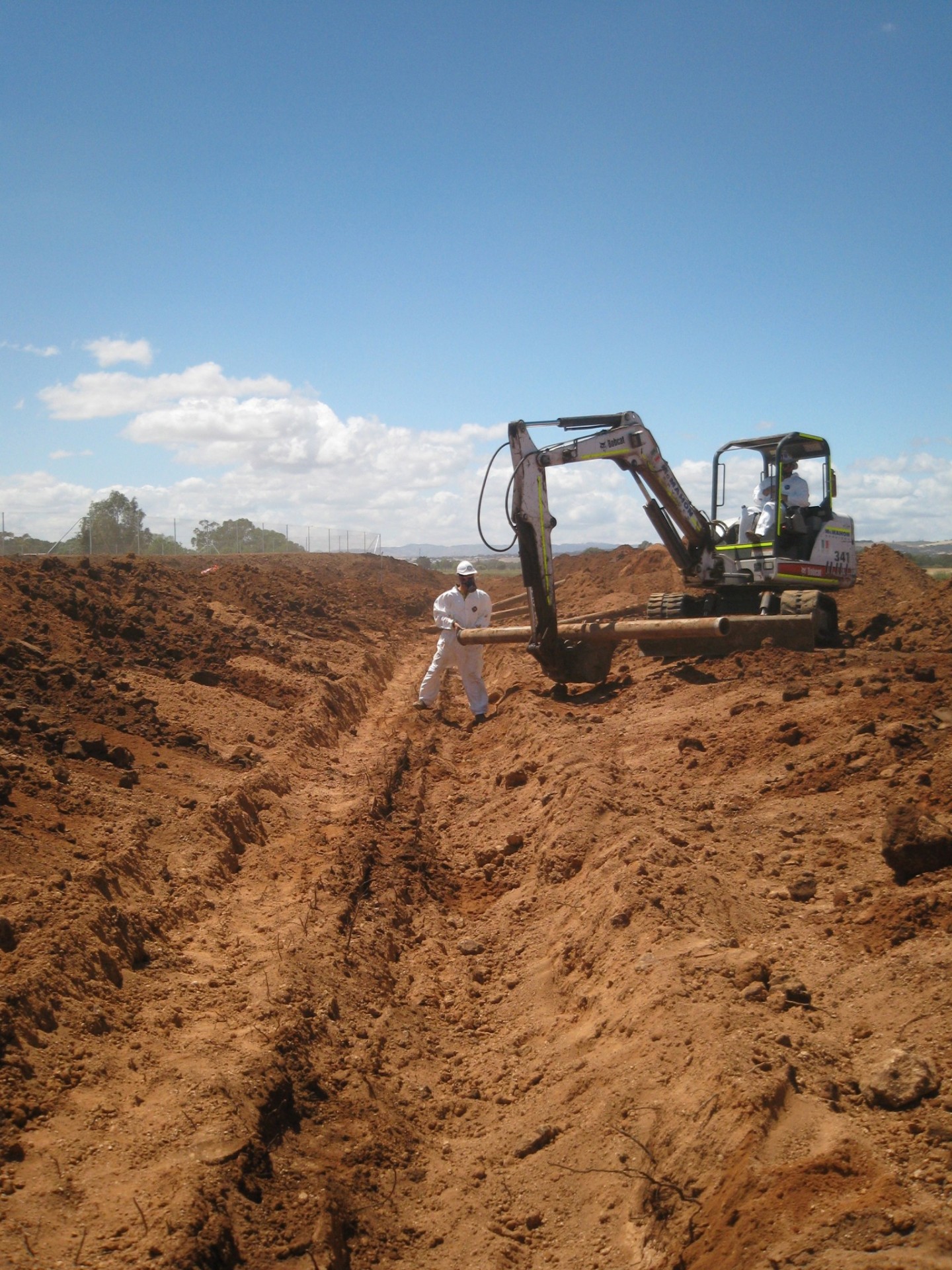 Rural pipe instillation by a man in a white suite and white crane